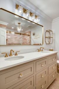 Elegant bathroom vanity with a double sink, quartz countertop, brushed‑gold faucets, and a large framed mirror with crystal-accented lighting above.