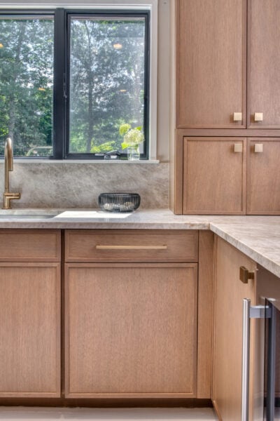 Close‑up of rift‑cut oak cabinetry and stone countertop next to a window with natural light.