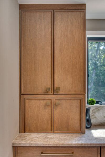 Closed view of full‑height rift‑cut oak cabinetry with upper and lower storage compartments.